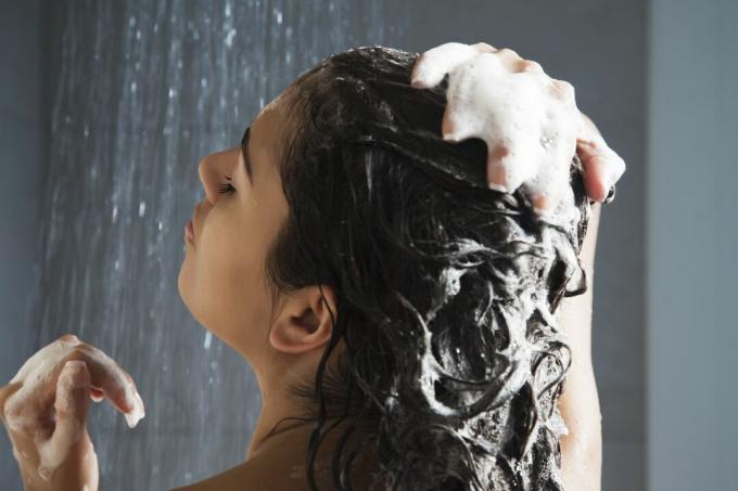 Mujer lavándose el cabello en la ducha