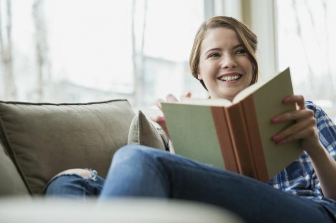 Mujer leyendo un libro en el sofá en la sala de estar
