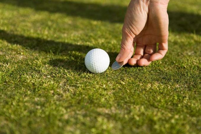 Oseba, ki označuje položaj žogice za golf na zelenici