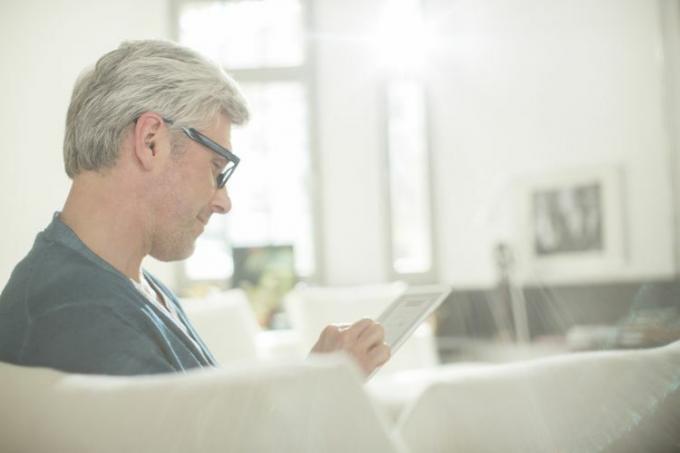 Homme lisant sur une tablette dans le salon