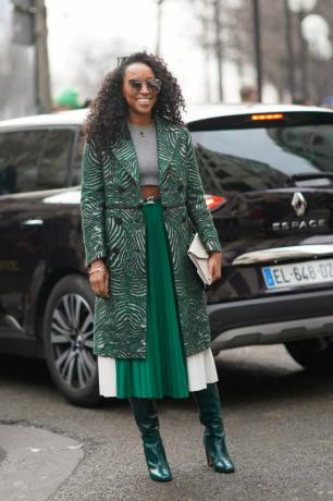 Mujer de estilo urbano con falda plisada verde y abrigo estampado