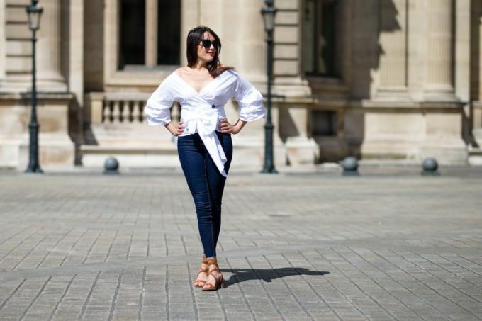 Ielas stila sieviete baltā blūzē un šauros džinsos