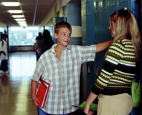Tonåringar (13-15) pratar i gymnasiets korridor, nära skåp