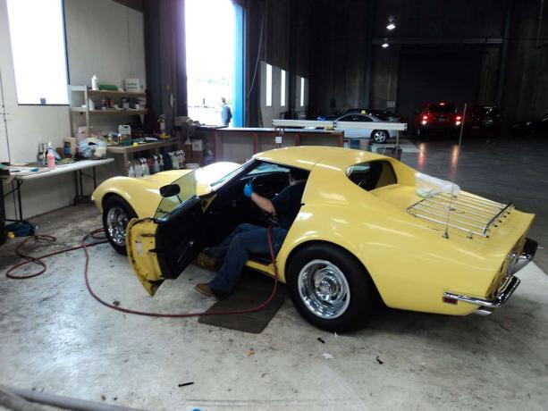 Man die 1969 Corvette in de winkel schoonmaakt.