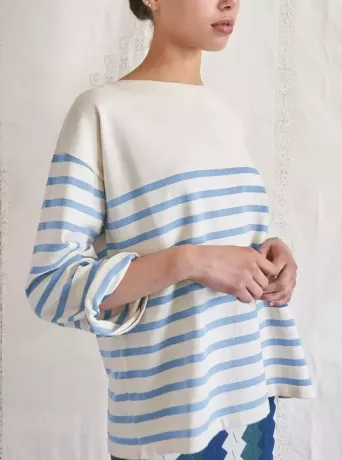 En model iført en creme- og lyseblå stribet sweater. 