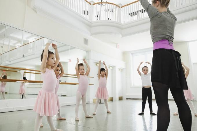 Kvindelig balletinstruktør underviser børn i balletstudie