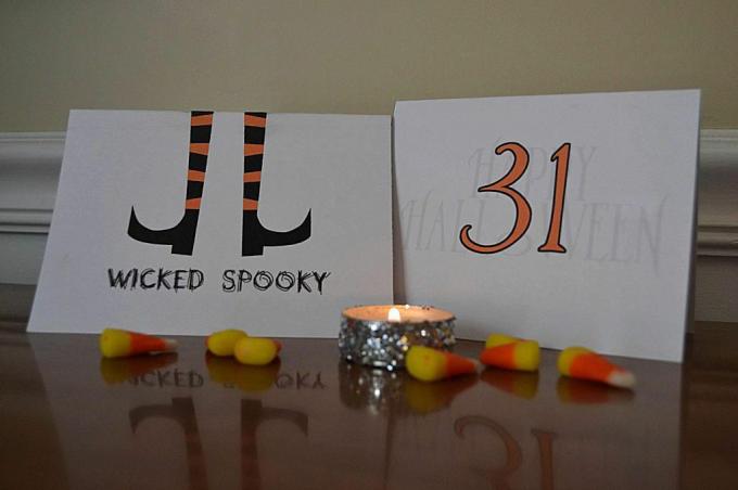 Twee Halloween-kaarten zittend op een tafel met snoepgraan en een kaars.