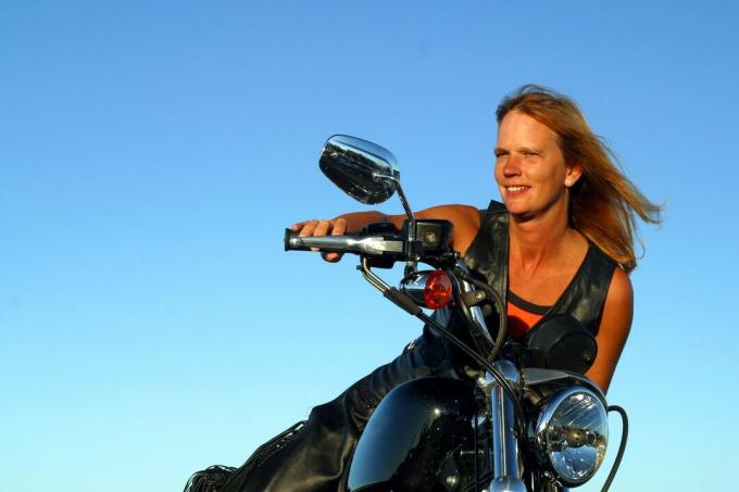 साफ आसमान वाली मोटरसाइकिल पर बैठी महिला