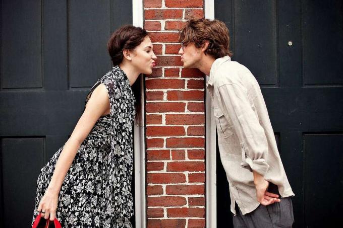 Bir tuğla sütunun önünde erkek arkadaşına veda öpücüğü veren bir model